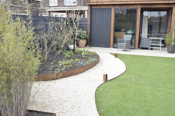Goed onderhouden tuin met gemaaid gazon en verzorgde borders bij een moderne woning