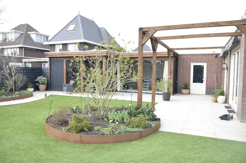 Royale tuin met ronde borders, pergola en gazon in Berkel en Rodenrijs