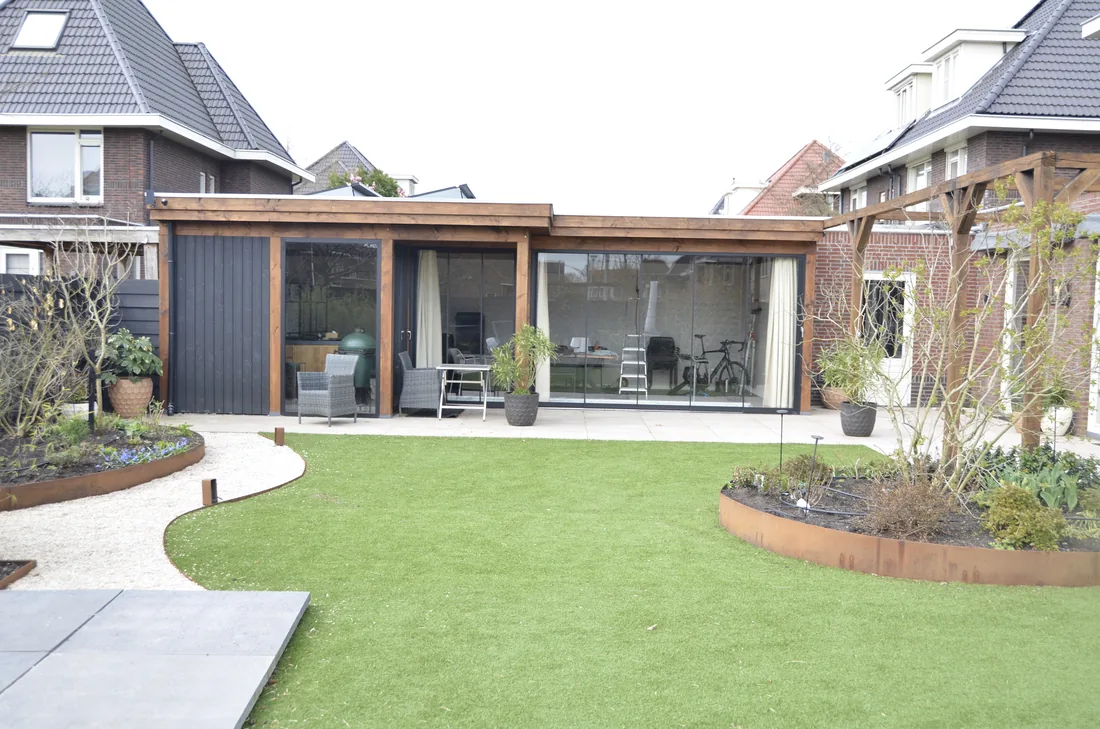Complete tuinaanleg met veranda, gebogen gazon en borders in Berkel en Rodenrijs